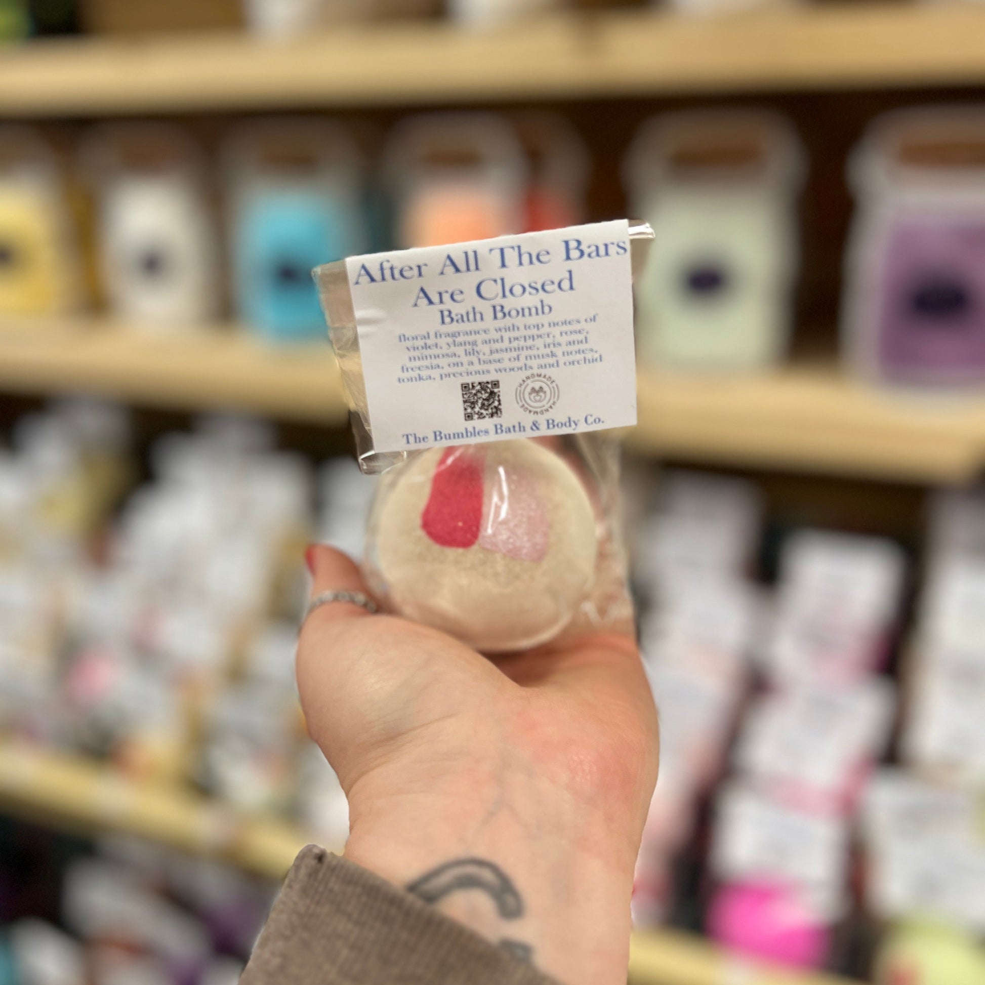 Hand holding a bath bomb with a label in a store setting