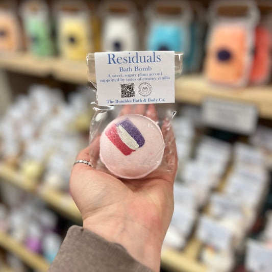 Hand holding a Residuals bath bomb with a blurred store shelf in the background