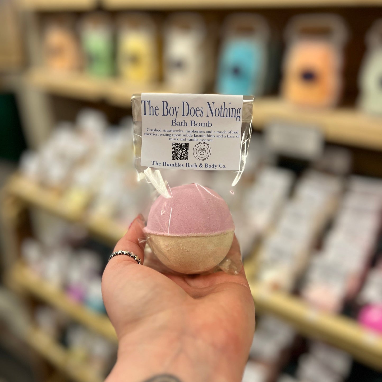 Hand holding a bath bomb with a label in a store setting