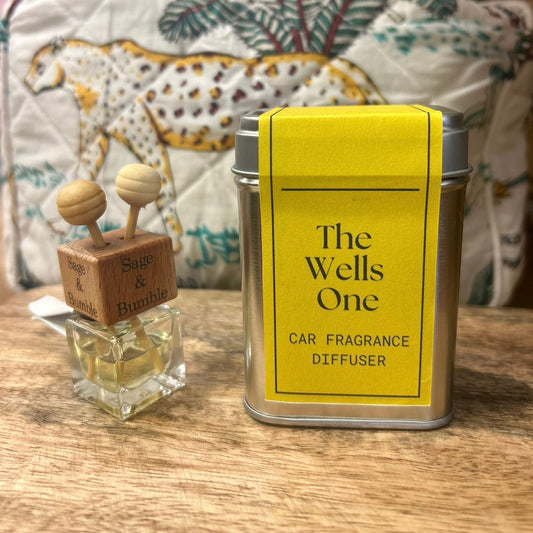 Sage and Bumble The Wells One handcrafted car air freshener.  The Car Air vent diffuser bottle sits beside the metal tin on wooden table